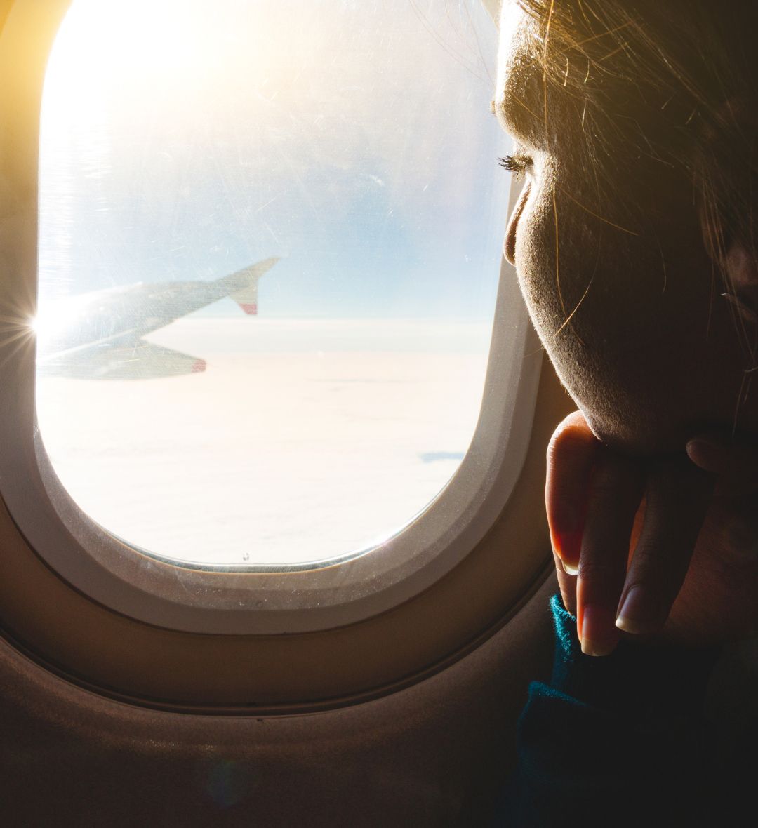 Mulher olhando pela janela do avião em direção ao horizonte